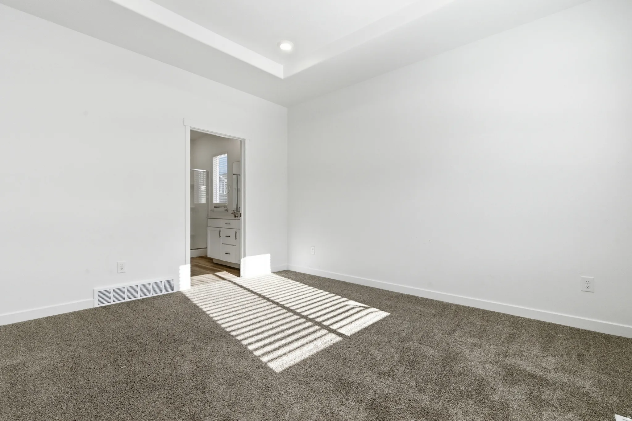 Carpeted interior space featuring a tray ceiling with recessed lighting