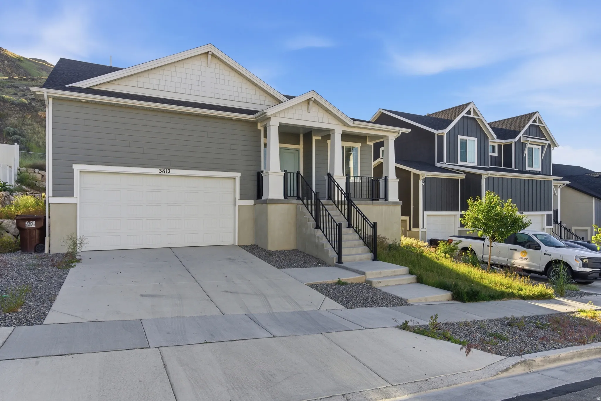 Contemporary residence featuring gray siding, a prominent two-car garage, and a covered entry porch with white columns and black railings