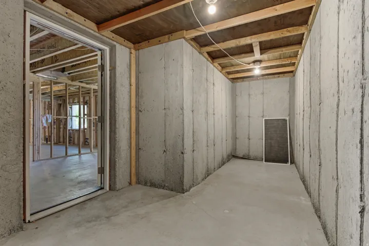 Unfinished basement featuring concrete walls, concrete flooring, and exposed ceiling joists