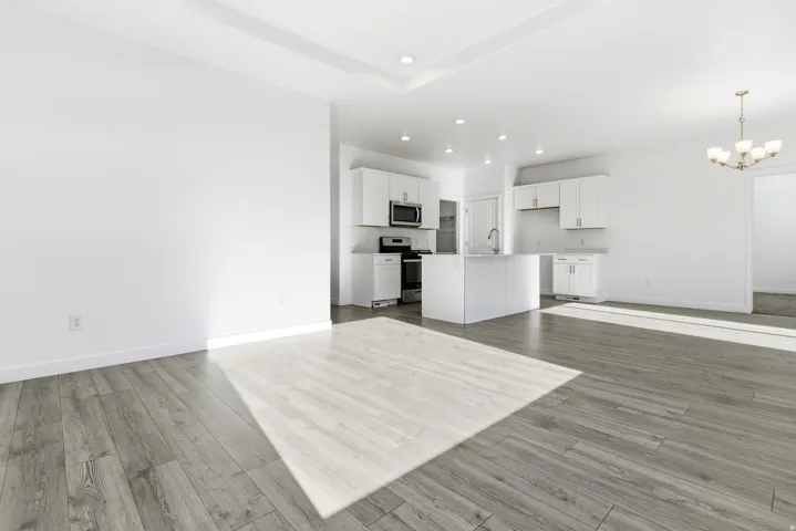 Open-concept living area featuring wood-finish flooring and a tray ceiling