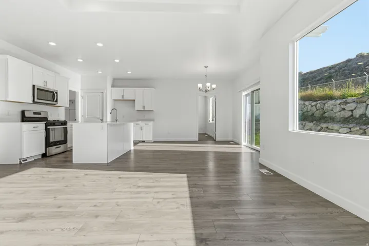 Open-concept living space with wood-finish flooring, recessed lighting, and a tray ceiling
