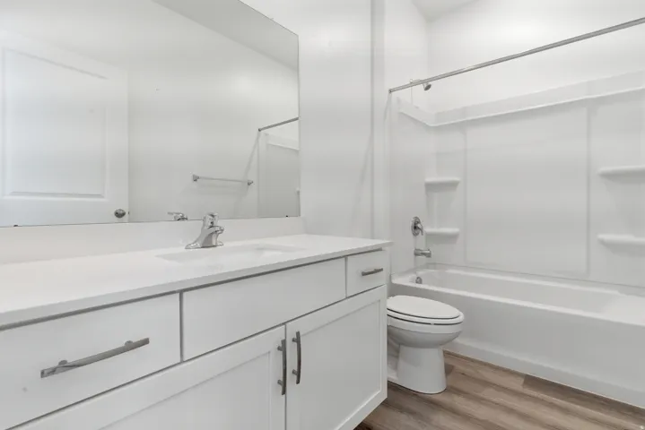 Bright bathroom featuring a white vanity with integrated sink, chrome faucet, and expansive mirror