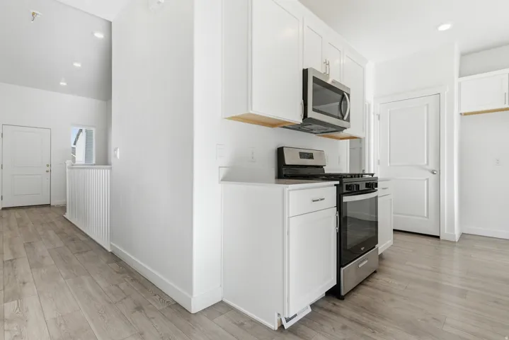Kitchen featuring stainless steel appliances, white cabinetry, and light wood-finish flooring