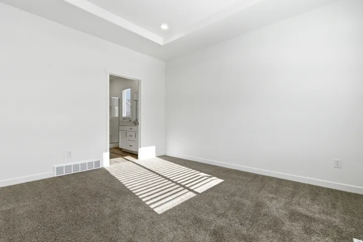 Carpeted interior space featuring a tray ceiling with recessed lighting