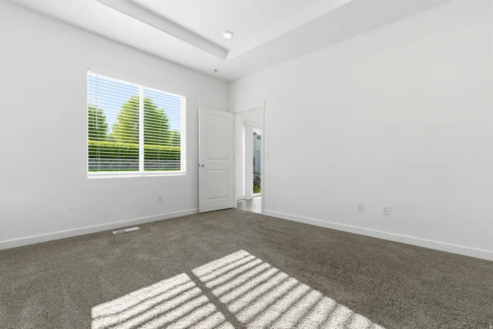 Carpeted room with a recessed tray ceiling and recessed lighting
