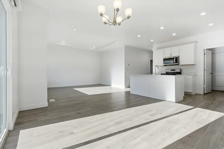 Open-concept living space featuring wood-finish flooring, recessed lighting, and a modern kitchen island with an undermount sink
