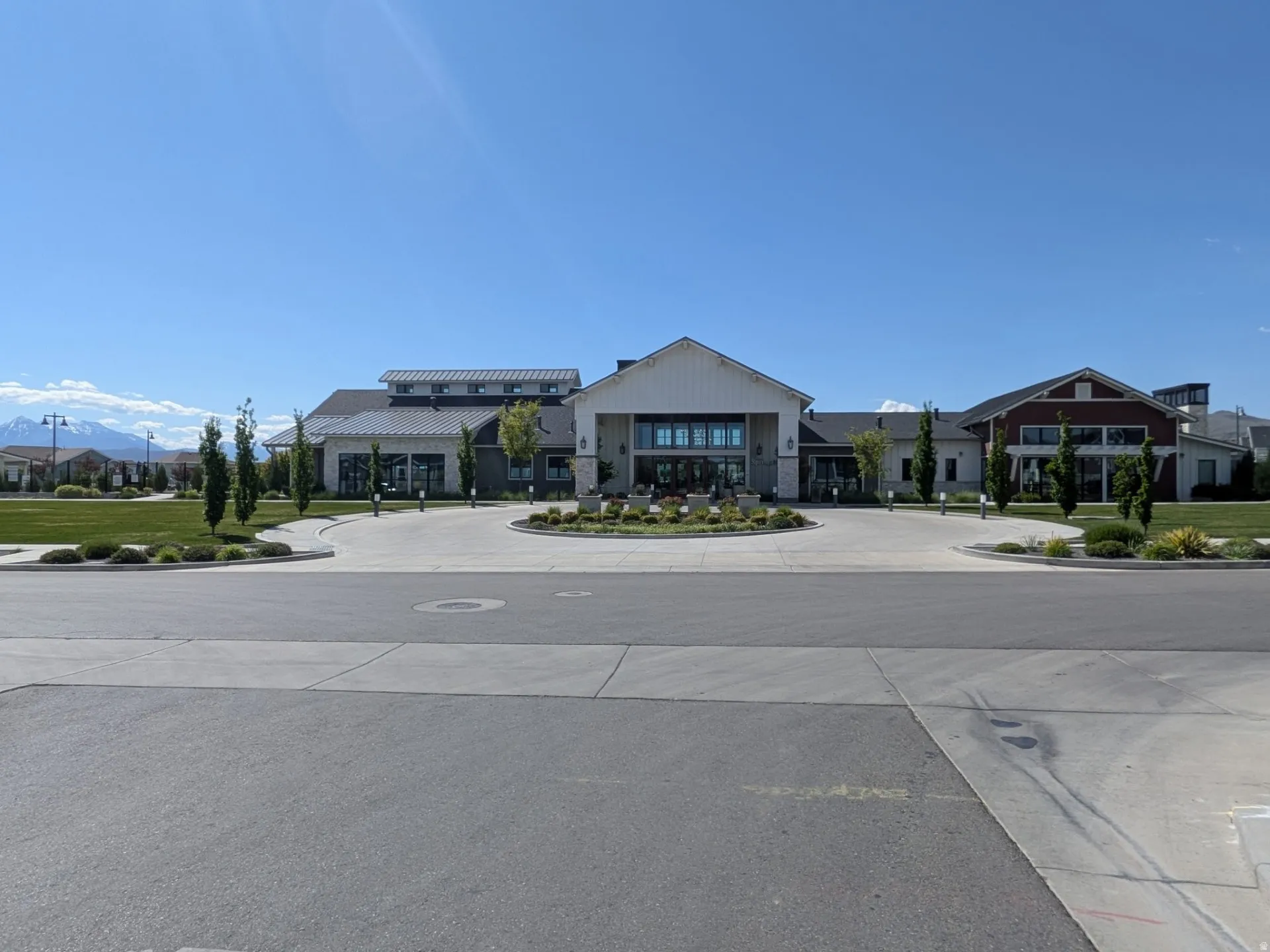 Expansive clubhouse building featuring a circular drive, multiple gabled rooflines, and a combination of horizontal siding and stone veneer
