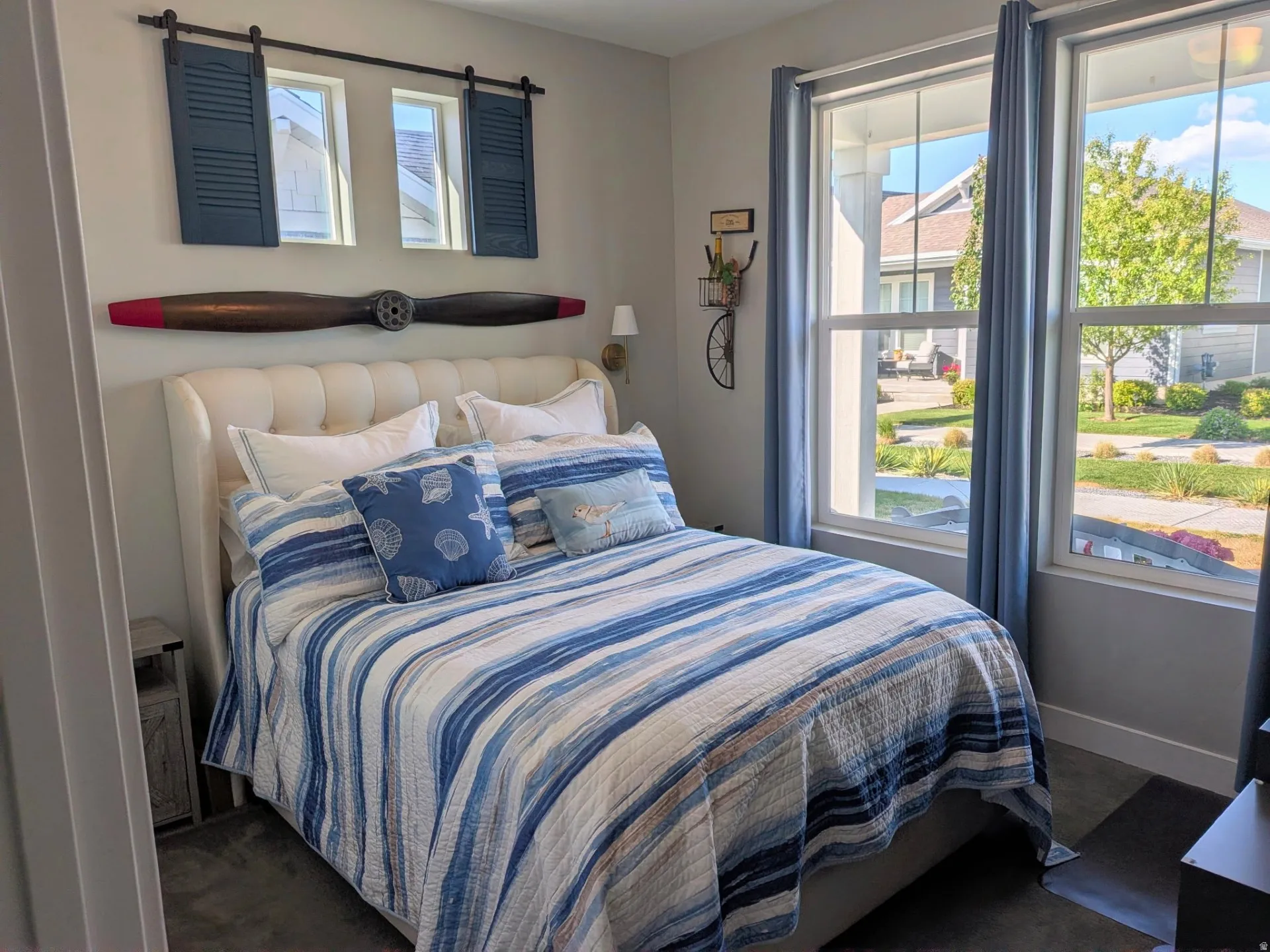 Bedroom featuring two large windows with blue drapes, and an upholstered headboard