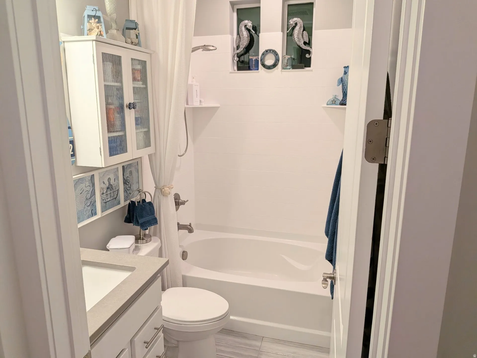 Bathroom featuring a white vanity with a light-toned countertop, a built-in tub with shower, and tiled flooring