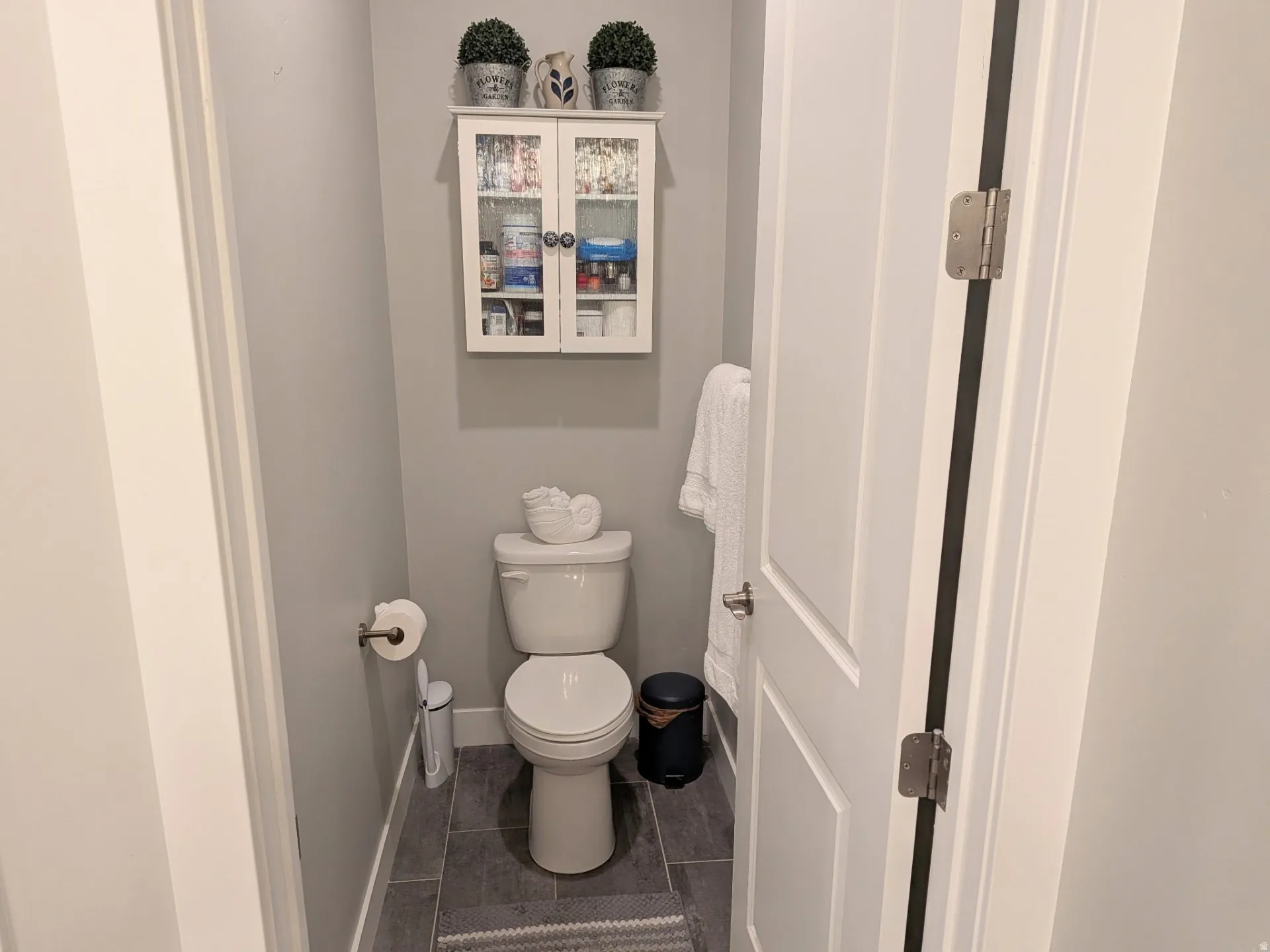 Powder room featuring a white toilet, gray wall color, and dark gray tile flooring