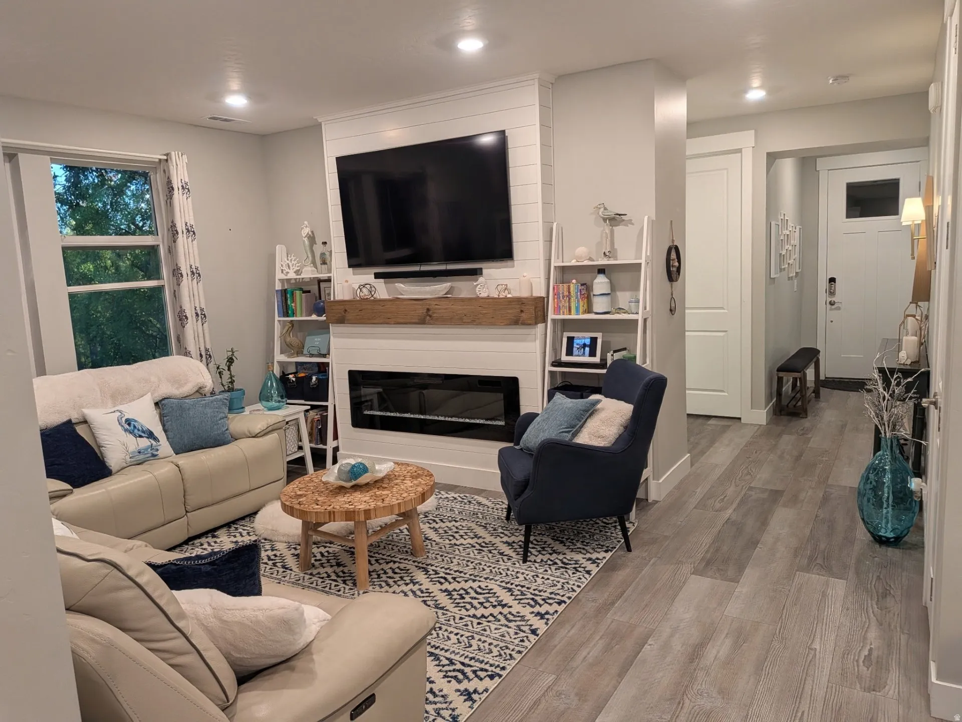 Living area featuring a shiplap fireplace surround with a wood mantel, an electric fireplace insert, recessed lighting, and wood-finish flooring