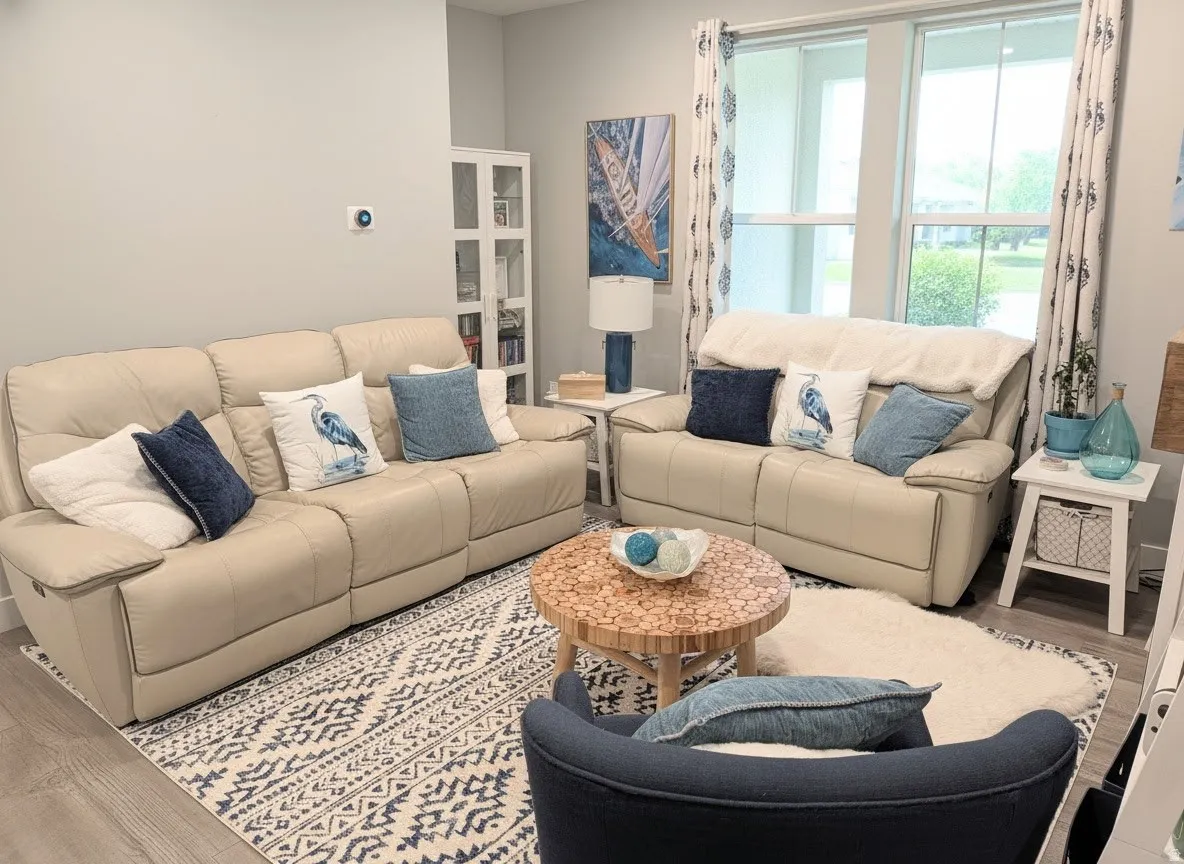 Spacious room featuring wood-finish flooring, a patterned area rug, and large windows with vertical blinds and decorative drapes