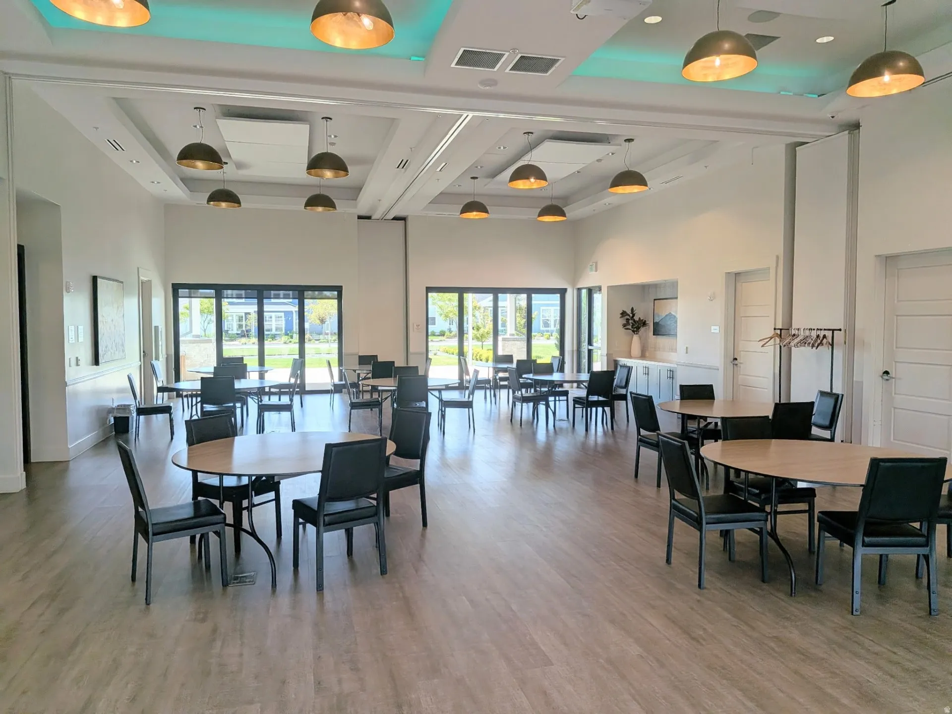 Spacious common room featuring wood-finish flooring, recessed lighting, and multiple pendant light fixtures