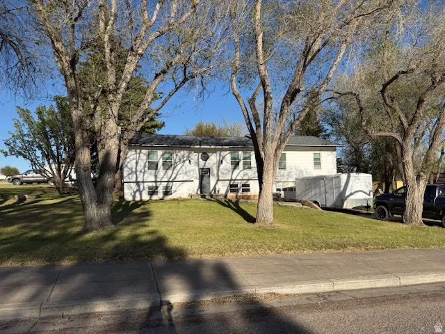 White exterior residence with a dark entry door, multiple windows, and a prominent front lawn