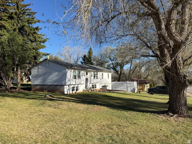 Two-story residential structure featuring white siding, multiple windows, a dark roof, and a front entrance with steps