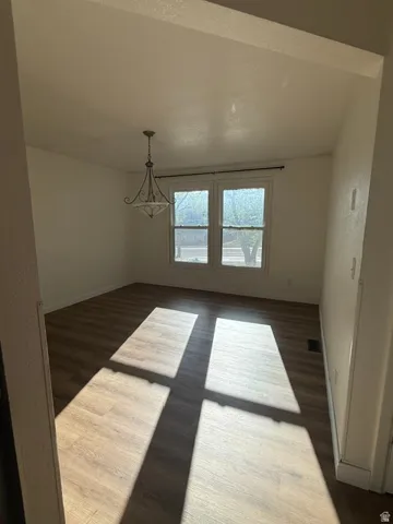 Wood-finish flooring, white walls, dual windows, and an overhead chandelier