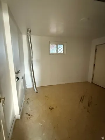 Utility room with a window, white walls, and a door with a brass-finish knob
