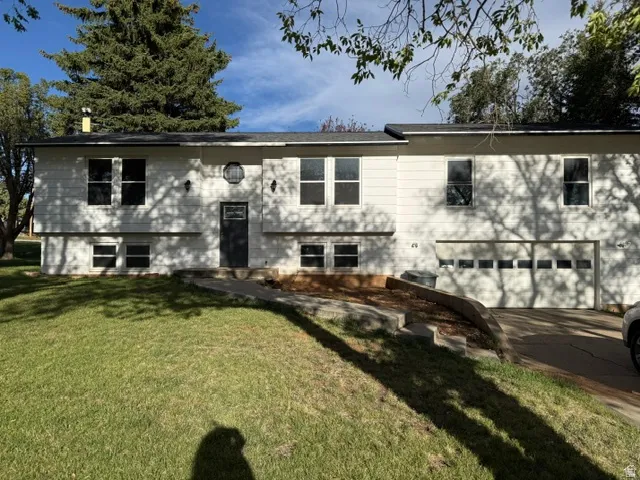 Split-level residence featuring a two-car garage, white siding, and a dark entry door with an oval window