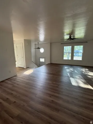 Wood-finish flooring throughout, bright interior with large windows, overhead ceiling fans, and a white paneled door