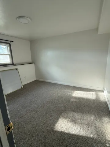 Neutral wall paint, window with dark trim, recessed ceiling light, and gray carpet flooring