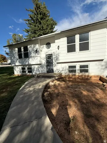 White exterior siding with dark trim windows, front entry door, and exterior lighting fixtures