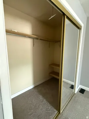CLOSET IN MASTER BEDROOM- Mirrored sliding closet doors with gold-tone framing, integrated shelving, and a built-in hanging rod