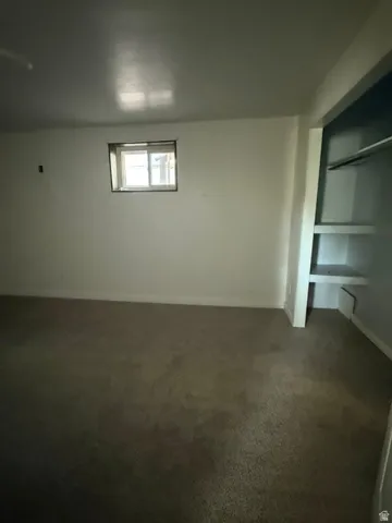 Carpeted flooring, white walls, built-in shelving, and a window