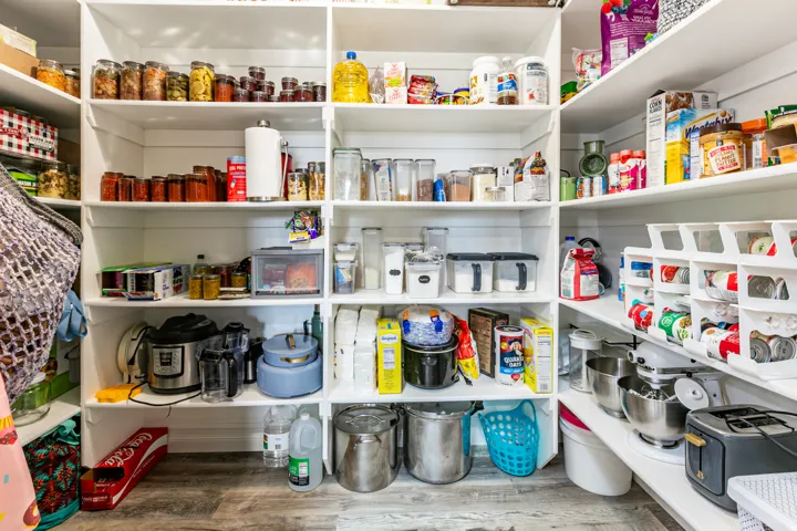 Expansive pantry featuring multi-level open shelving, shiplap wall finishes, and wood-finish flooring