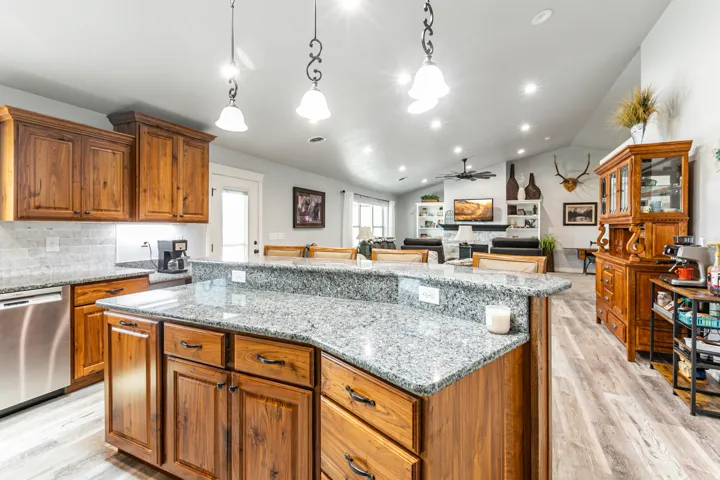 Kitchen island featuring a granite countertop with a raised bar and wood cabinetry