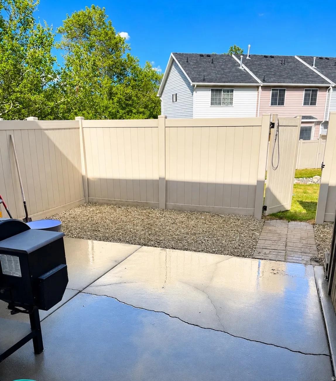 Paved patio space featuring a gravel-covered yard area, full privacy fencing, and a fenced gate providing exterior access