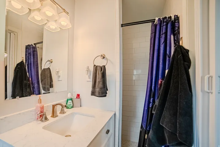 Bathroom vanity with a white countertop and rectangular undermount sink, complemented by a gold-toned faucet