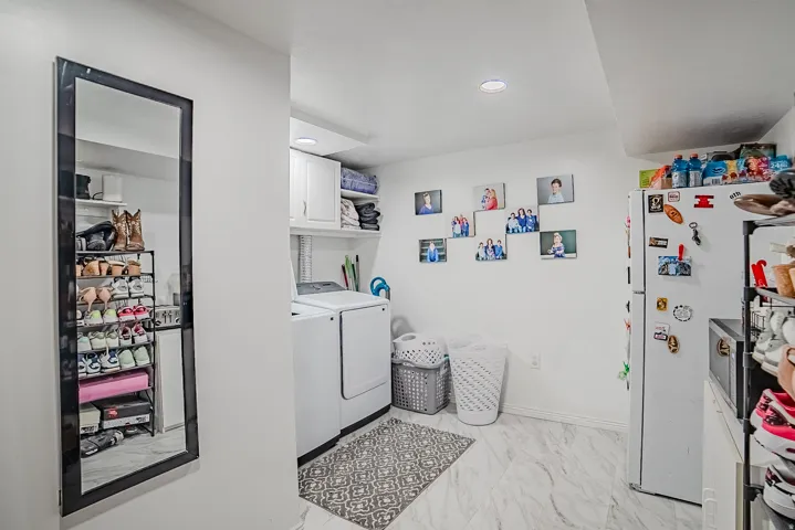 Laundry area featuring white cabinetry, a built-in shelving unit, and marble-look flooring