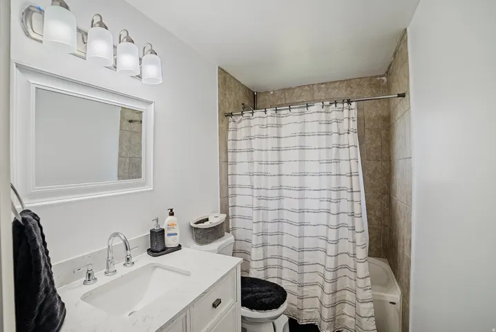 Bathroom featuring a white vanity with an integrated sink and chrome fixtures, a framed mirror, and a four-light fixture