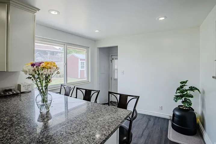 Kitchen featuring a granite-finish countertop, white cabinetry with crown molding, recessed ceiling lighting, and wood-finish flooring