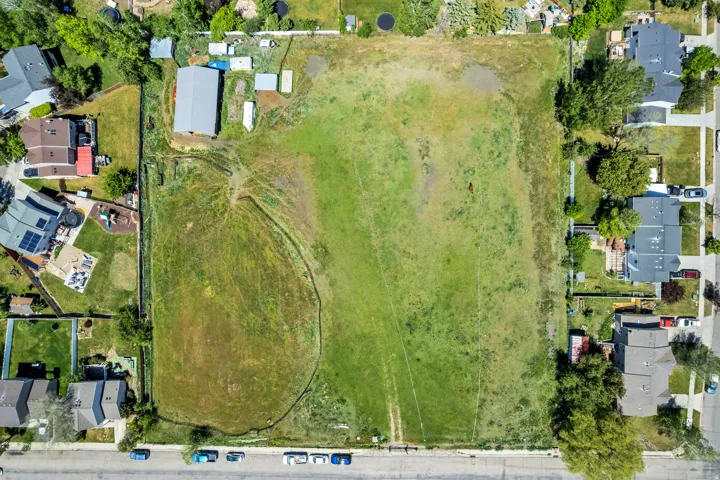 Expansive green field surrounded by residential properties and a paved road