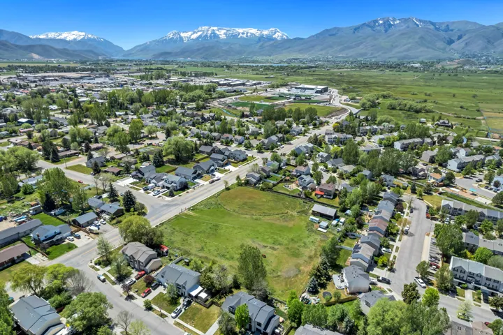 Aerial perspective showcasing a residential area surrounded by expansive green fields and mature trees