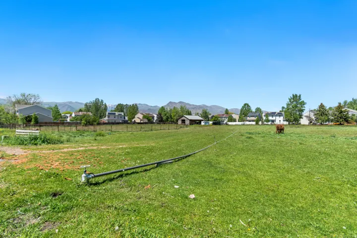 Expansive green space featuring a clear blue sky, distant mountains, and established perimeter fencing