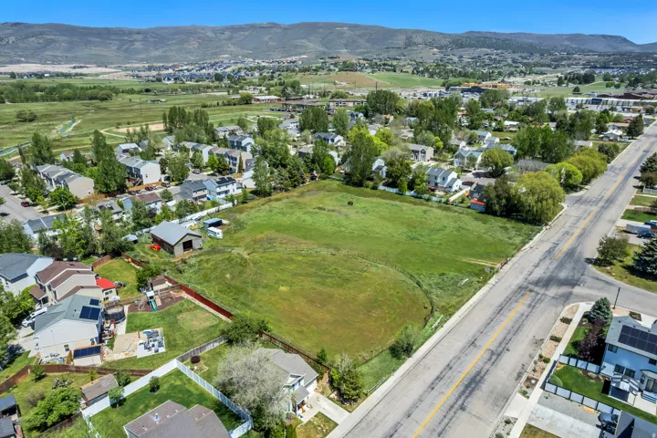 Expansive open land parcel featuring a lush green field, a detached barn structure, and surrounding residential properties