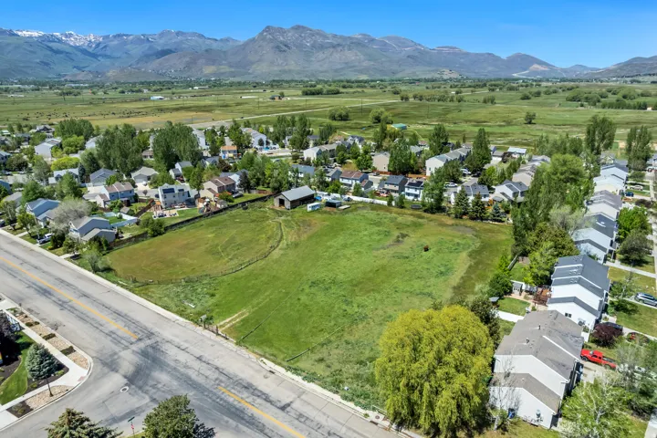 Expansive green space featuring a large field, a barn structure, and surrounding residential properties