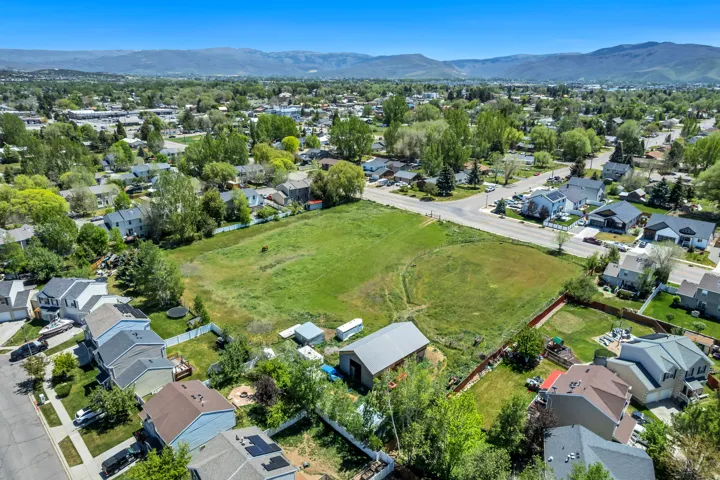Expansive green space featuring a barn structure and perimeter fencing, surrounded by established residential properties