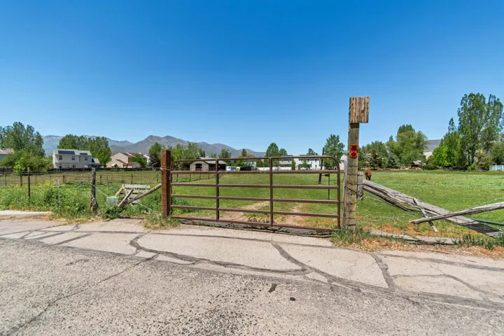 Expansive green space featuring a metal gate entrance to land and distant mountain backdrop