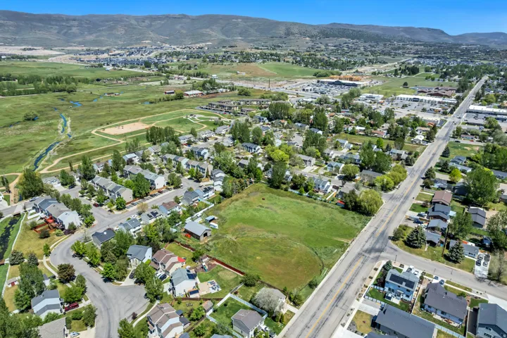Expansive aerial landscape featuring a residential neighborhood, green spaces, and mountain terrain in the background