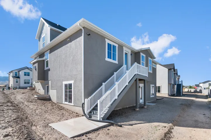 Stucco exterior with white trim, multi-pane windows, white deck railing, and exterior staircase