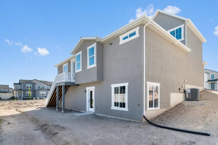 Multi-level stucco exterior with white trim windows and a white-railed upper deck