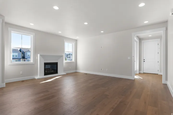 Wood-finish flooring, recessed lighting, and a white fireplace surround with a black insert
