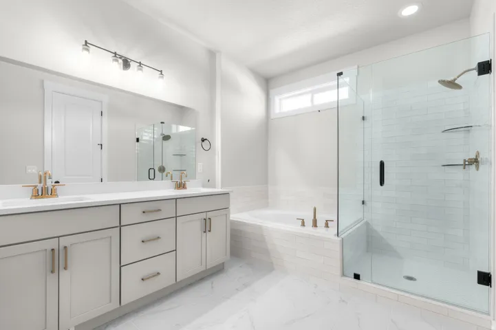 Dual vanity with white countertops, undermount sinks, and gold-finish faucets