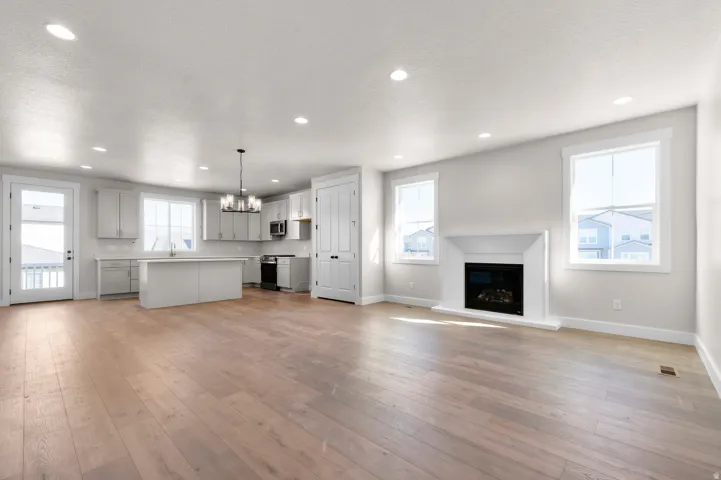 Open-concept living area with wood-finish flooring, a contemporary fireplace, and recessed lighting