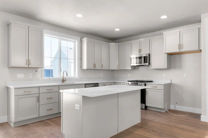 Spacious kitchen featuring an island, light-toned cabinetry, stainless steel appliances, white countertops, and wood-finish flooring
