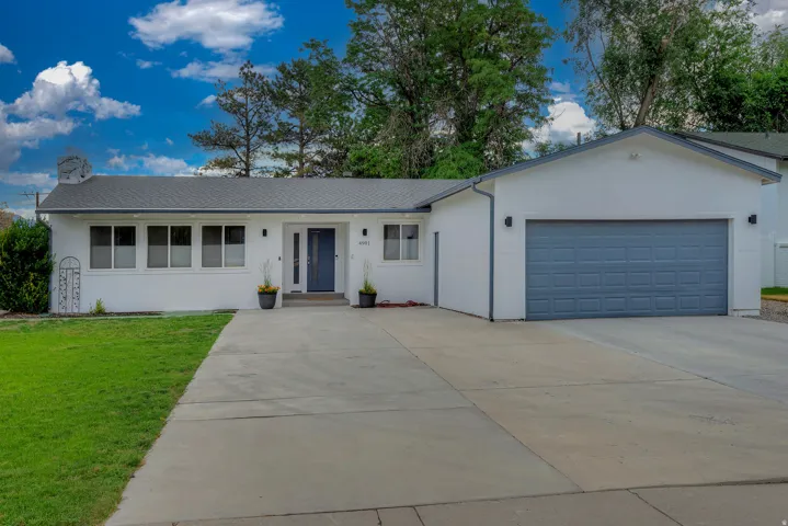 White stucco exterior with a dark gray shingle roof, featuring a gray two-car garage door