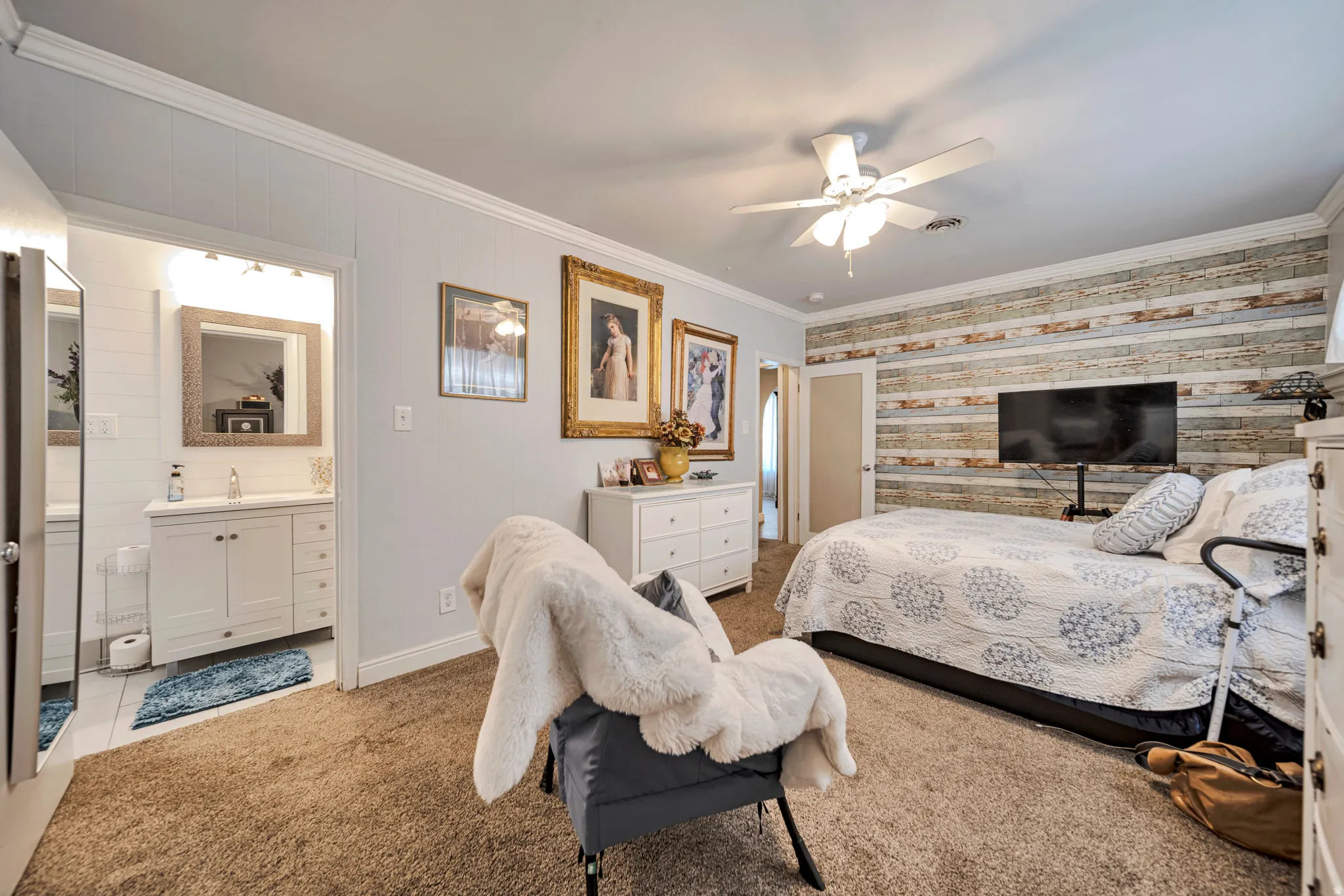 Spacious room featuring a decorative wood plank accent wall, plush carpet flooring, and a ceiling fan with integrated lighting